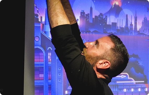 insight plus co-founder Tom Holtz reaching above his head out of frame with both hands with a roku idle screen on a tv in the background