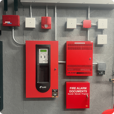 red fire alarm system control boxes on a cement wall