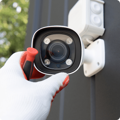 hand wearing a glove adjusting a wall mounted security camera